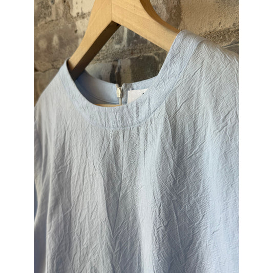 Women's violet top in blue from Secular, featuring a stylish design, displayed on a hanger against a neutral background.
