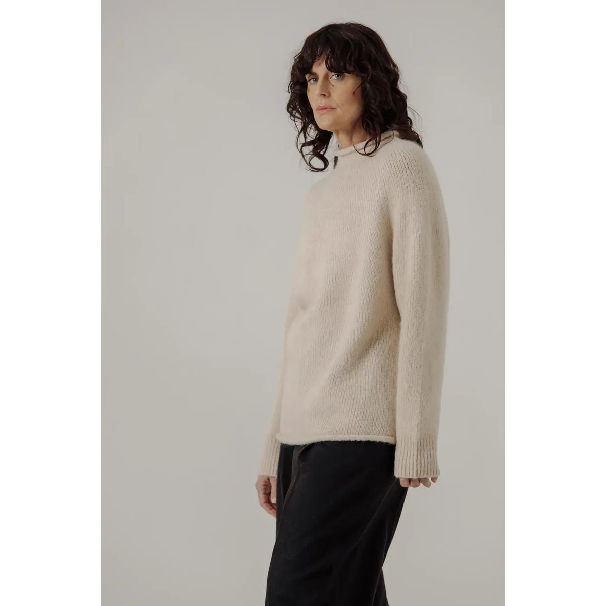 Cream women's handloom rollneck sweater by Bare Knitwear, showcasing its cozy knit fabric and high neckline.