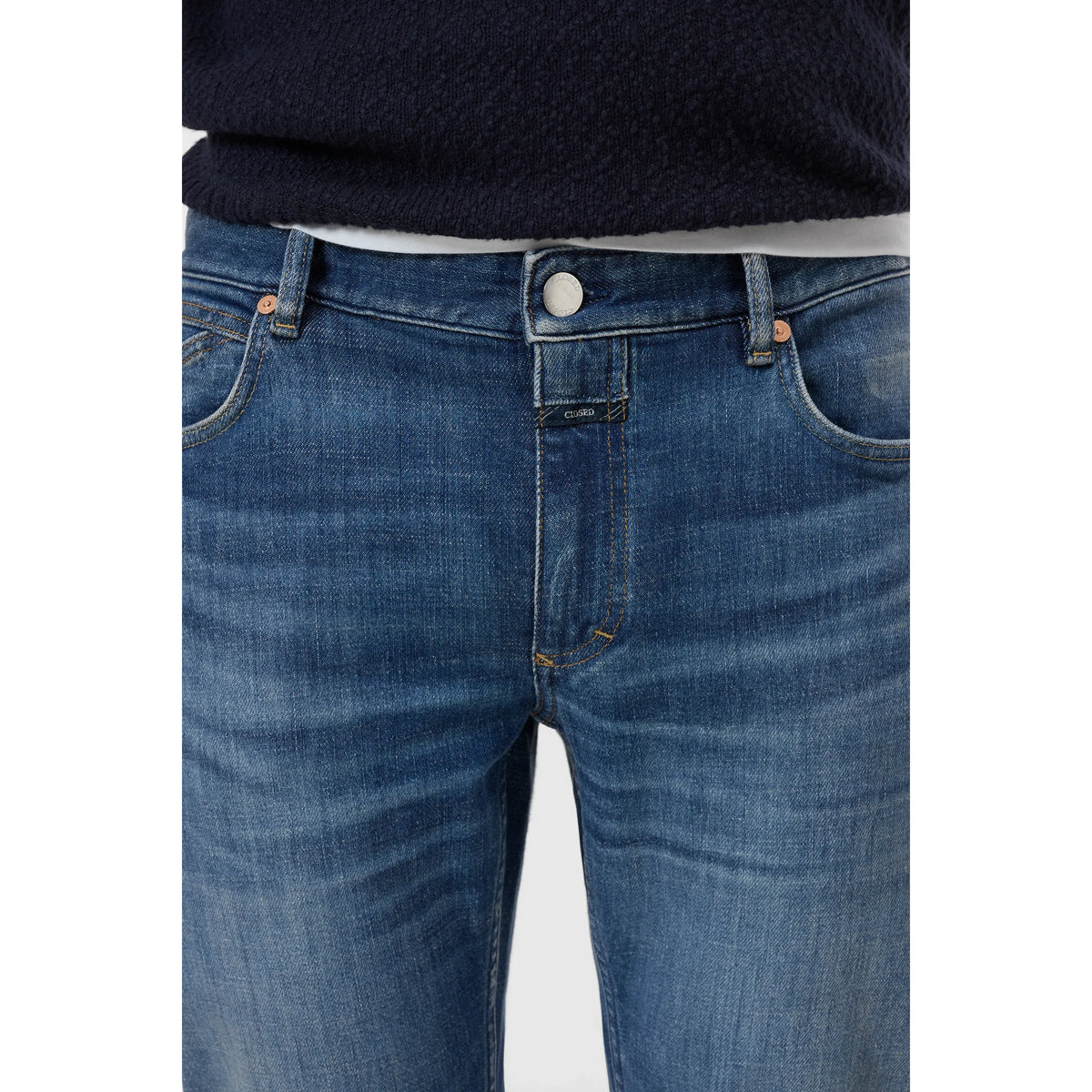 Men's Unity Slim Jean in mid blue denim by Closed Men's, showing a close-up of the fit and stitching details.