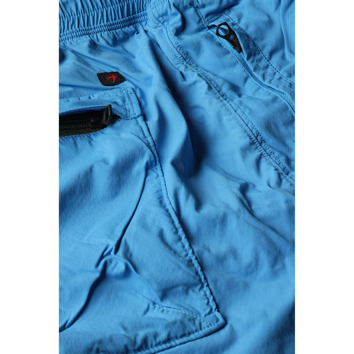 Men's Off-Trail Windpant by Relwen in bright blue, lightweight and wind-resistant with elastic cuffs and drawstring waist.