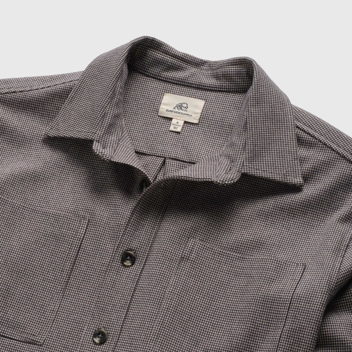 Men's Louis Soft Houndstooth Overshirt in ebony, featuring a classic pattern, made by Surfside Supply, displayed on a hanger.