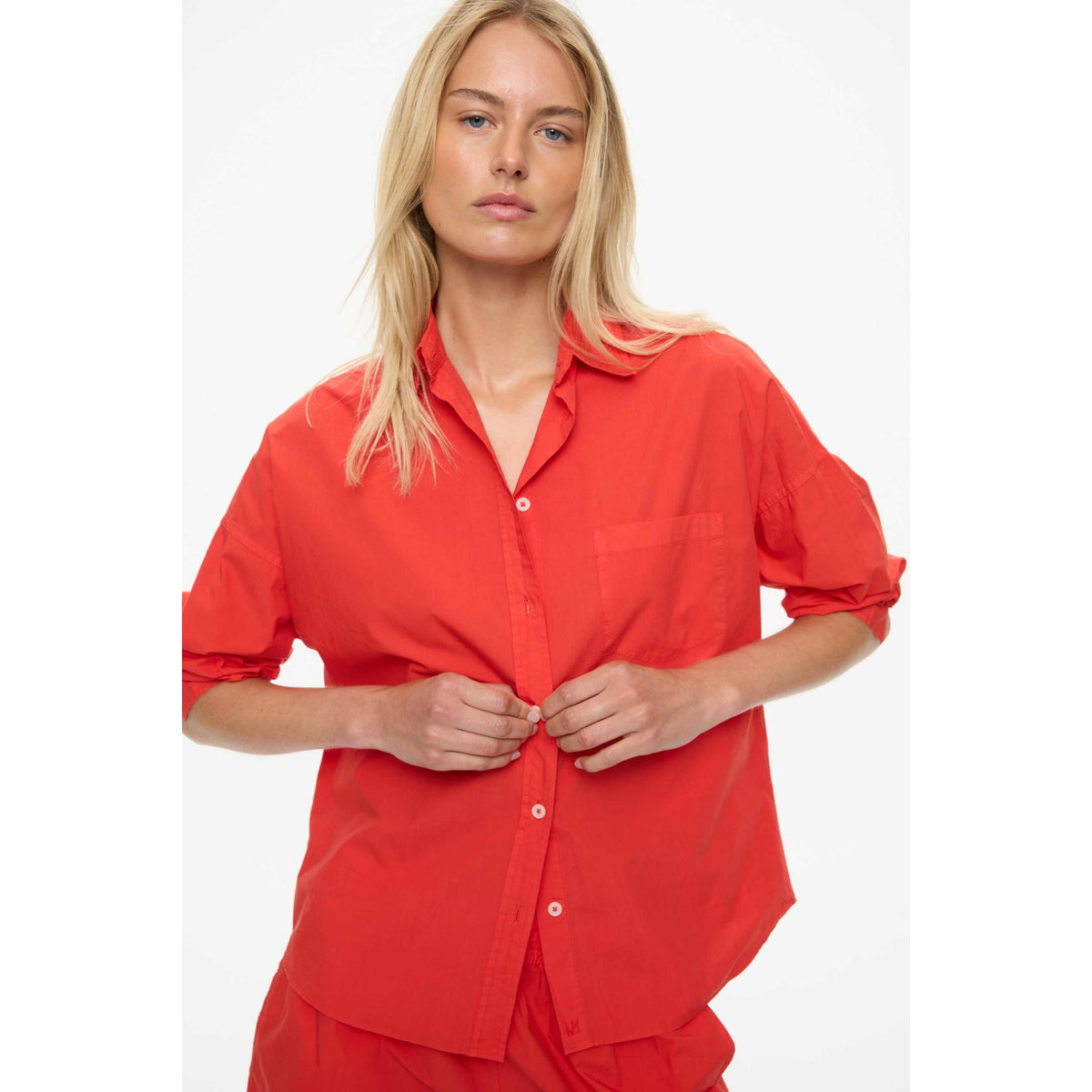 Women's Chiara Shirt in true red by LMND, featuring a stylish fit and vibrant color, shown on a model in a casual setting.