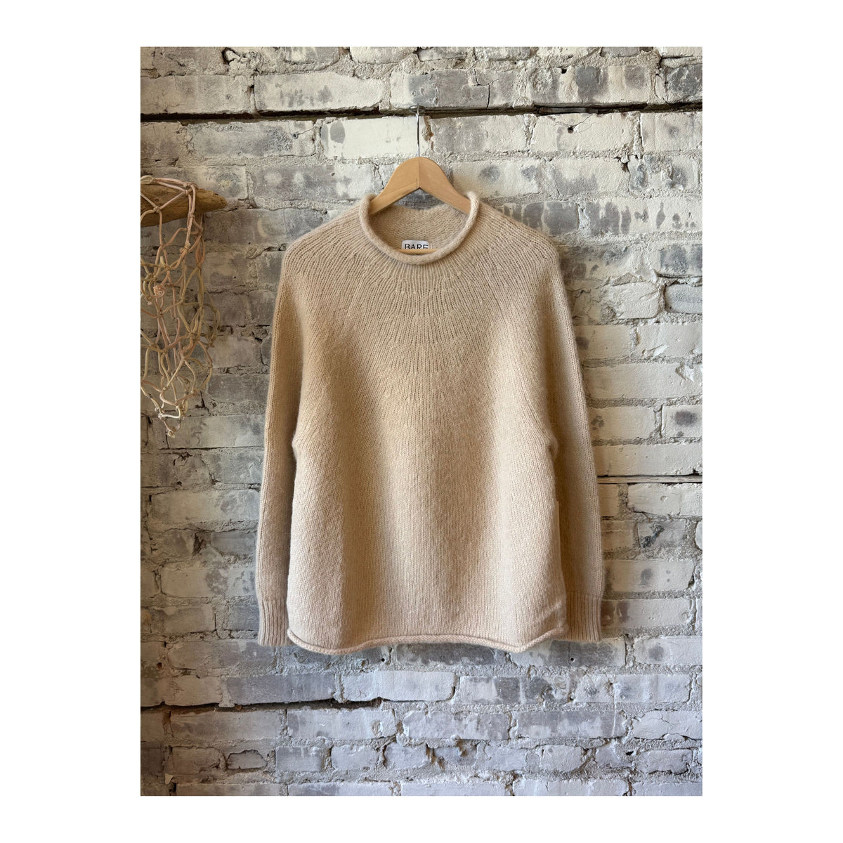 Cream women's handloom rollneck sweater by Bare Knitwear, showing the cozy knit fabric and fitted design.
