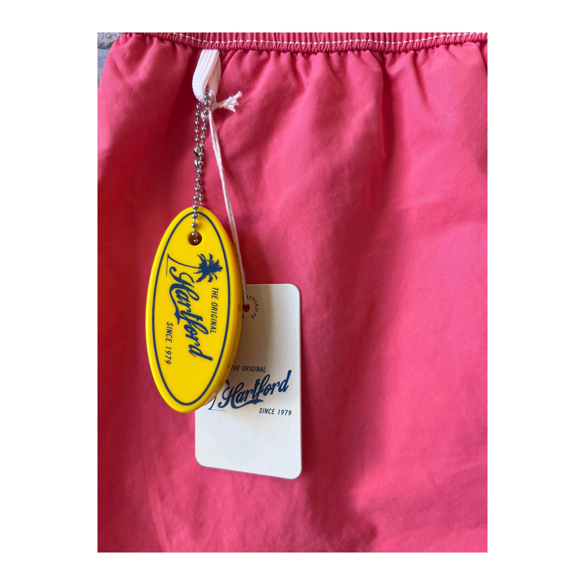 Men's Hartford Classic Swim Trunks in faded coral with matching pochette, featuring a relaxed summer style.
