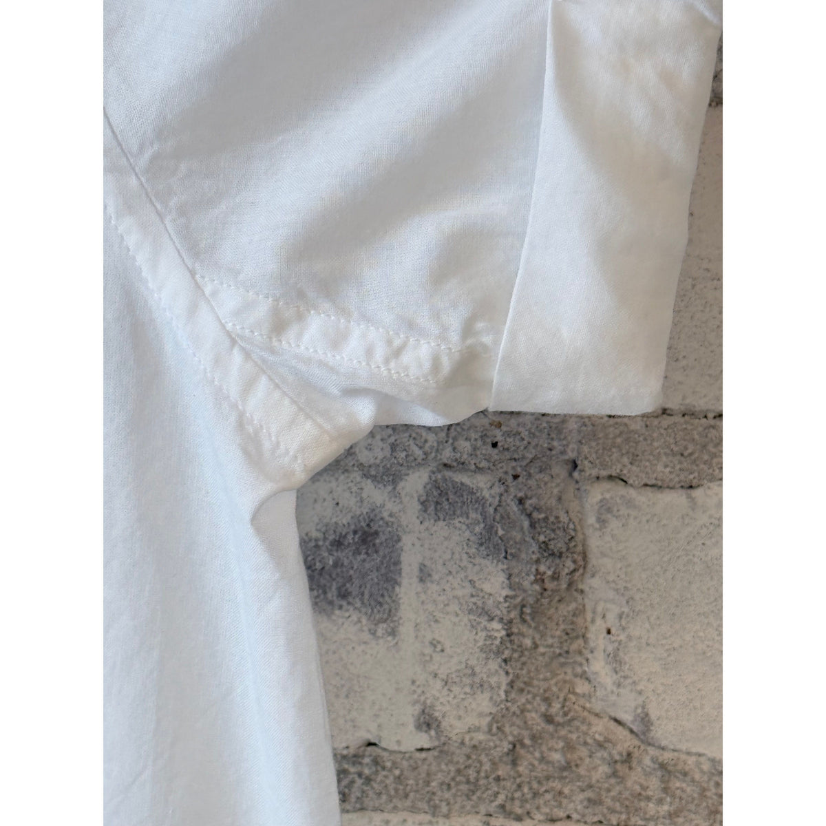 White lightweight cotton poplin women's shirt by Merz b. Schwanen with rolled-up sleeves, shown laid flat.