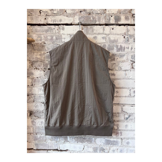 Men's beige nanamica zip-up wind vest, lightweight and weather-resistant, shown on a hanger with a smooth fabric texture.
