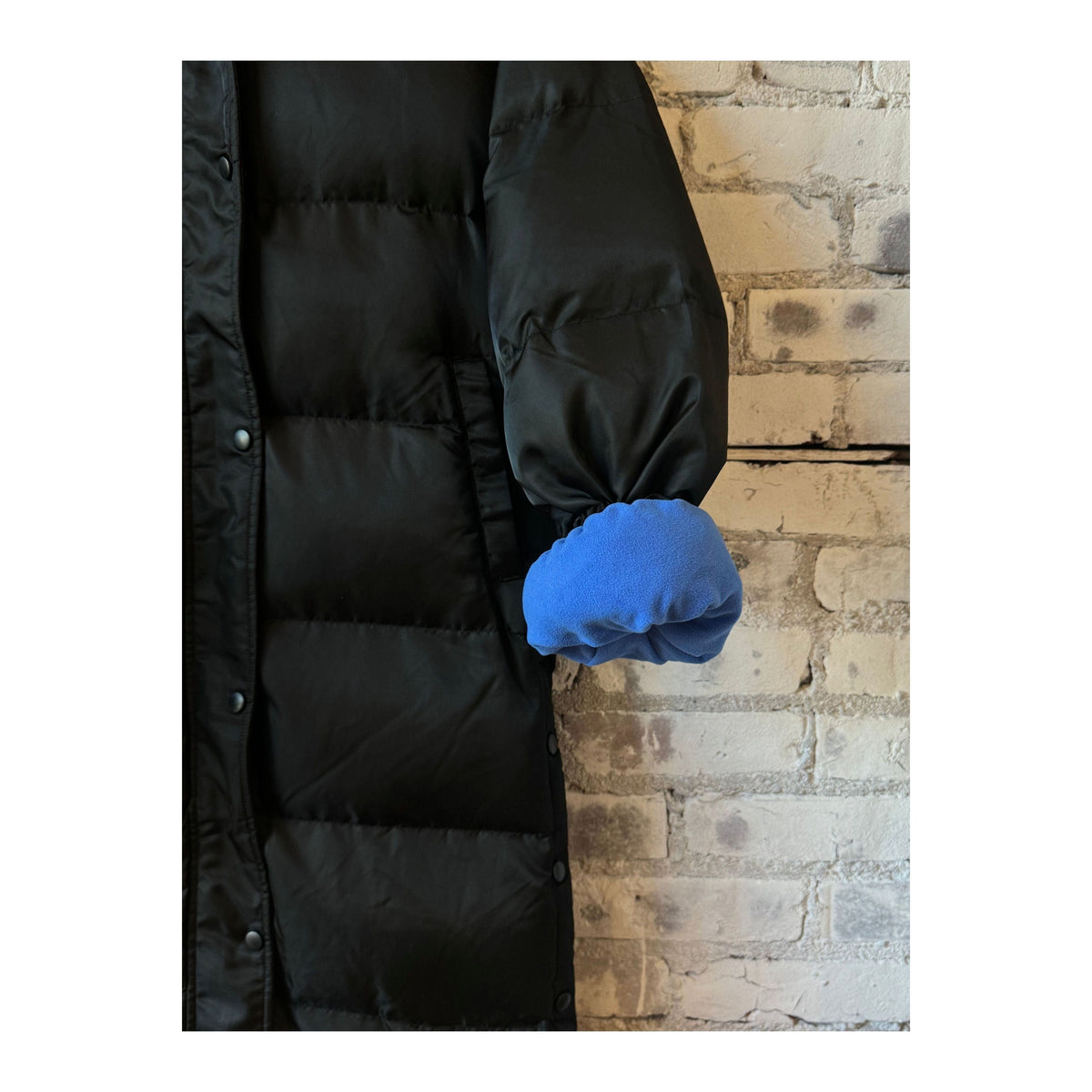 Women's long puffer jacket in black and royal blue by TWIN, showcasing a stylish, insulated winter coat with a high collar.
