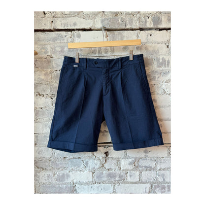 Men's navy seersucker Bermuda shorts with a relaxed fit, featuring light blue and white striped fabric and an elastic waistband.