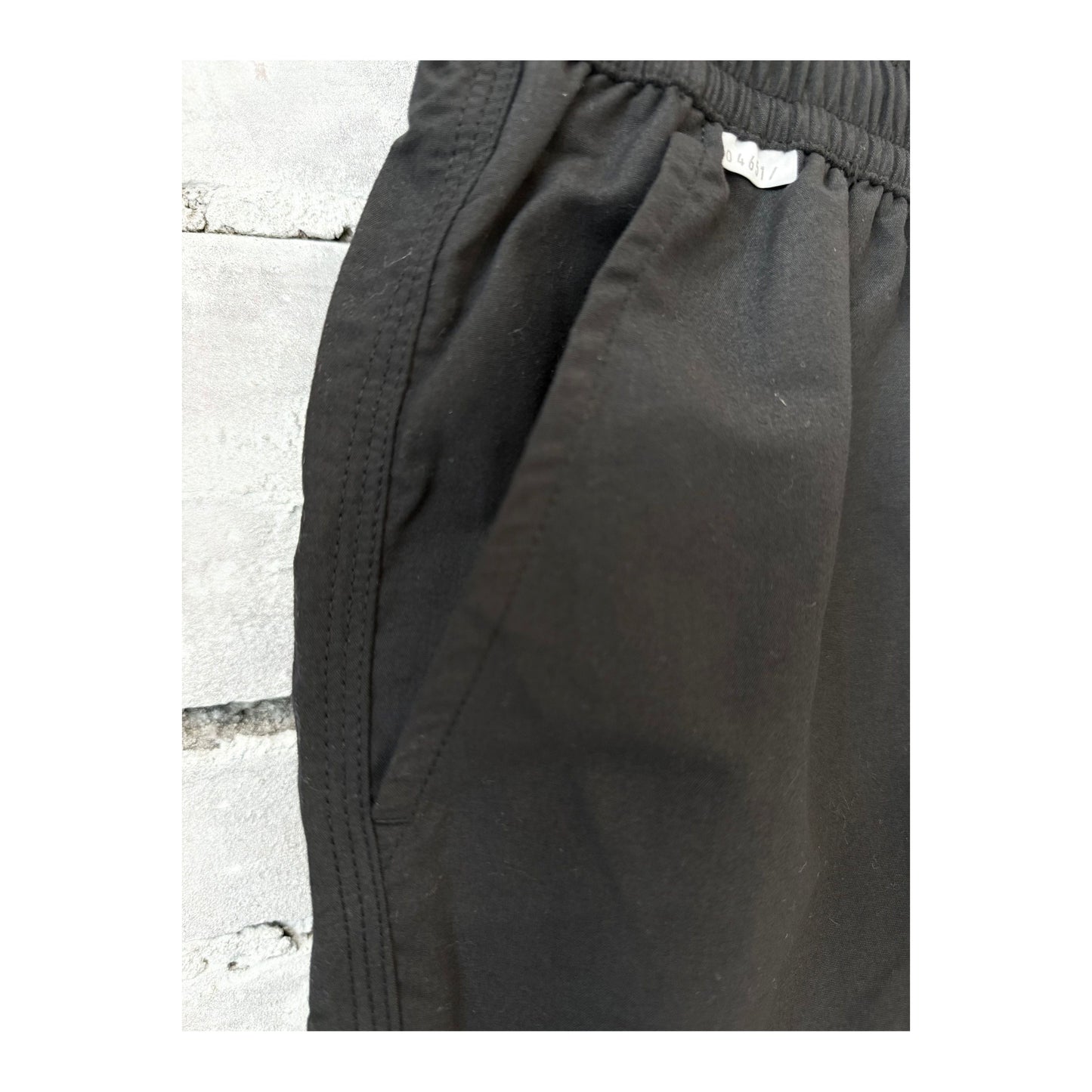 Men's black swim shorts with an elastic waistband and side pockets, designed for comfortable beach or poolside wear.