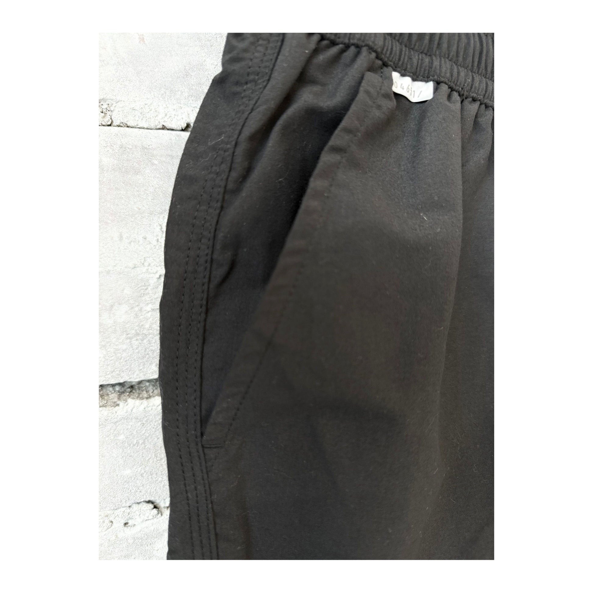Men's black swim shorts with an elastic waistband and side pockets, designed for comfortable beach or poolside wear.