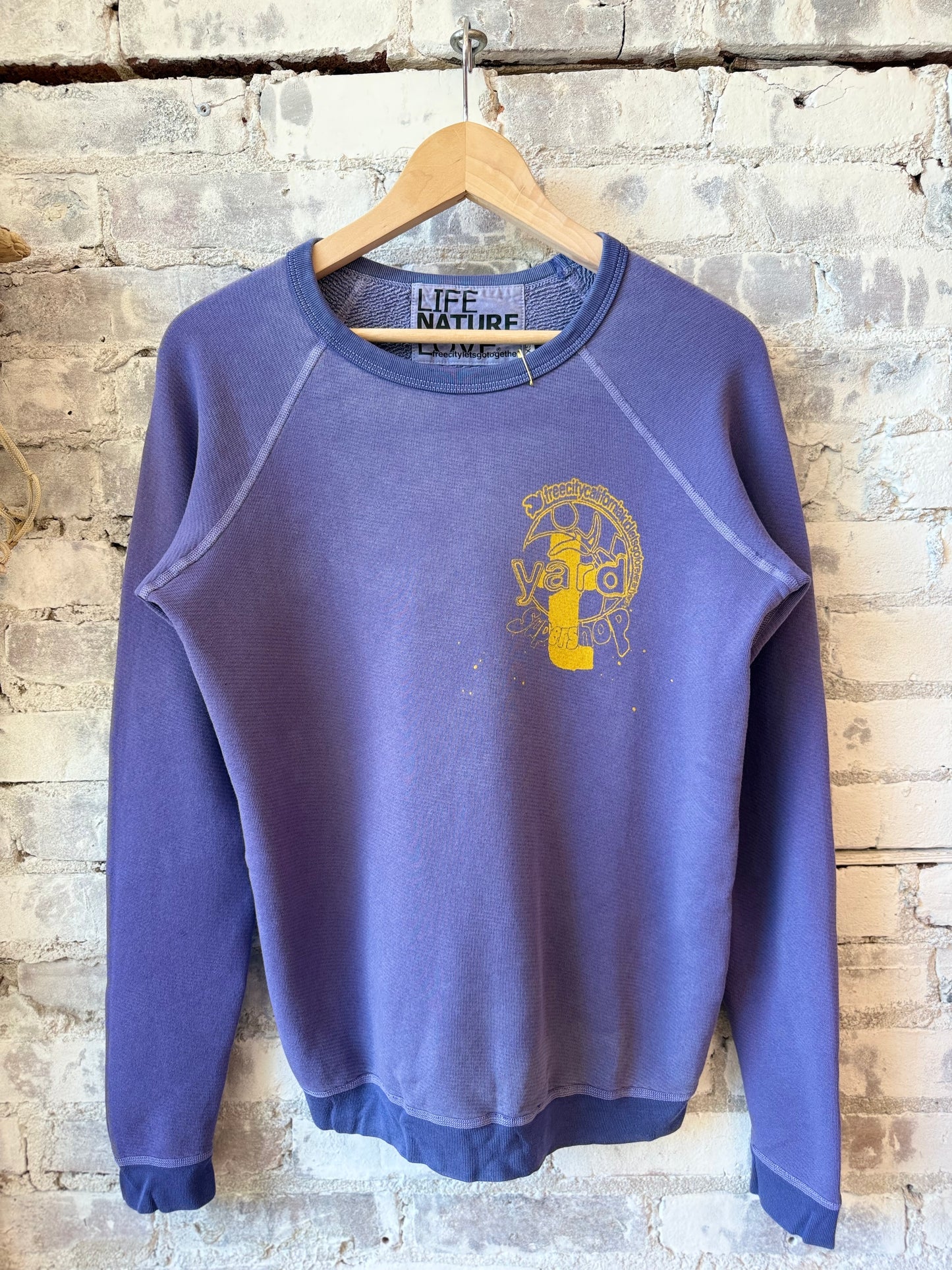 Women's purple raglan sweatshirt with "Freecity" branding and purple bush design, casual fit, front view.