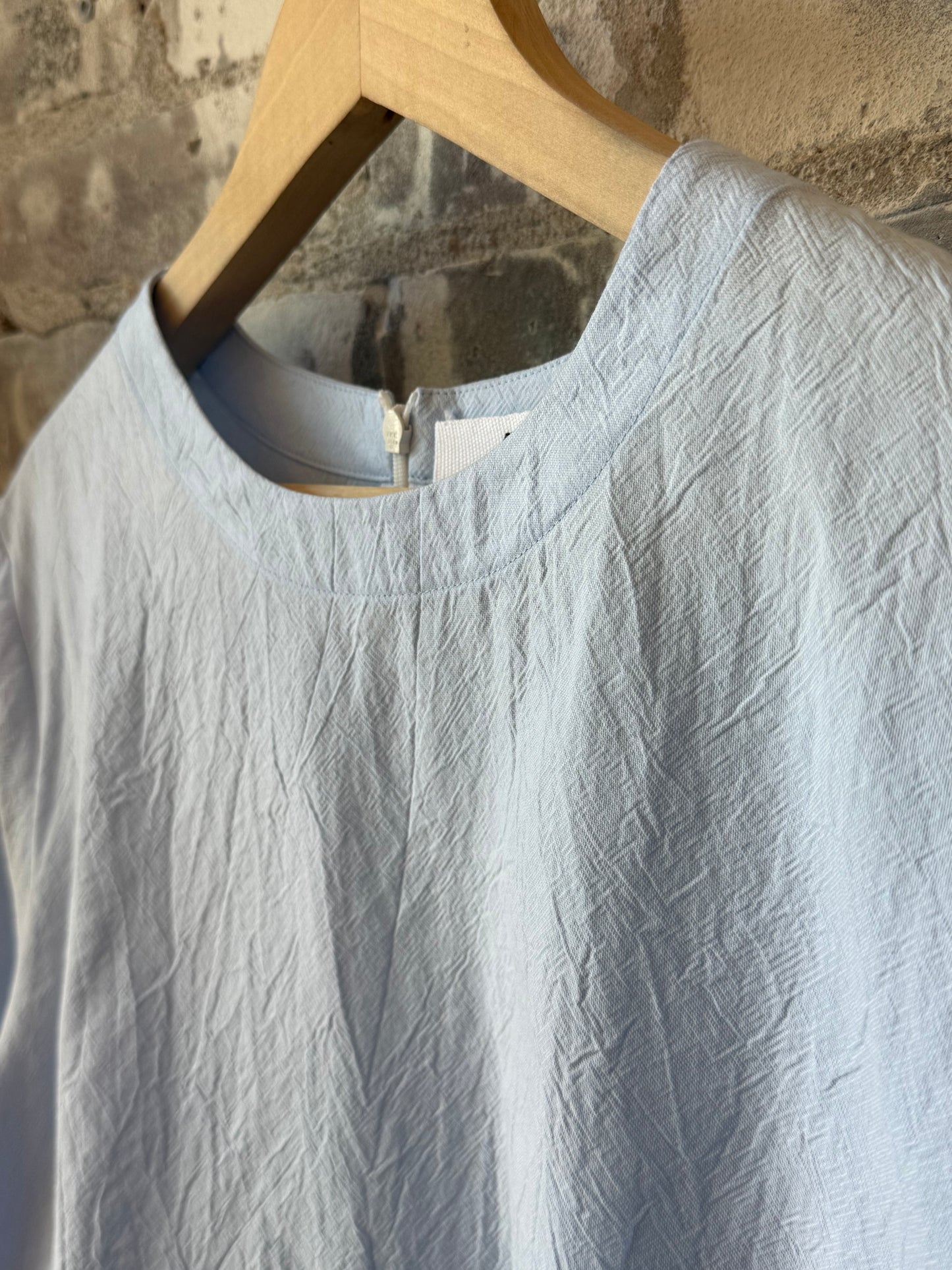 Women's violet top in blue from Secular, featuring a stylish design, displayed on a hanger against a neutral background.