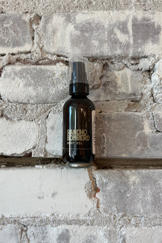 Rancho Bombero total body oil 2 oz. in a clear glass bottle with a pump dispenser, designed for skincare and body nourishment.