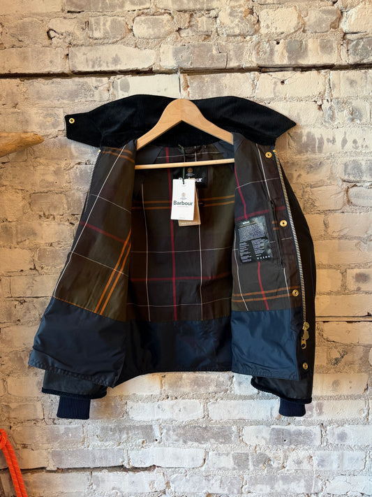 Women's navy Barbour Beadnell waxed jacket with cropped length and classic style, shown on a model outdoors.