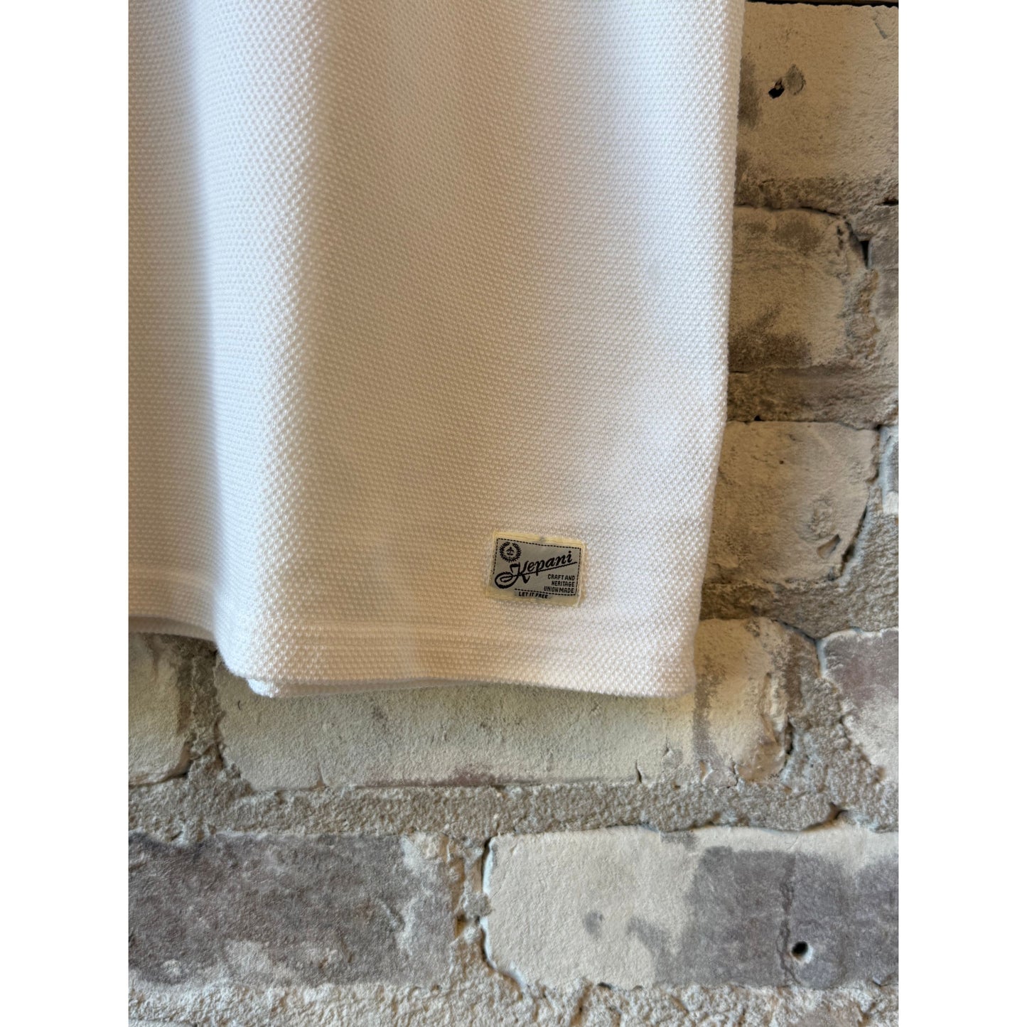 Men's white Raffy Pique Knit Polo Shirt by Kepani, featuring a classic collar and short sleeves, displayed flat on a neutral background.