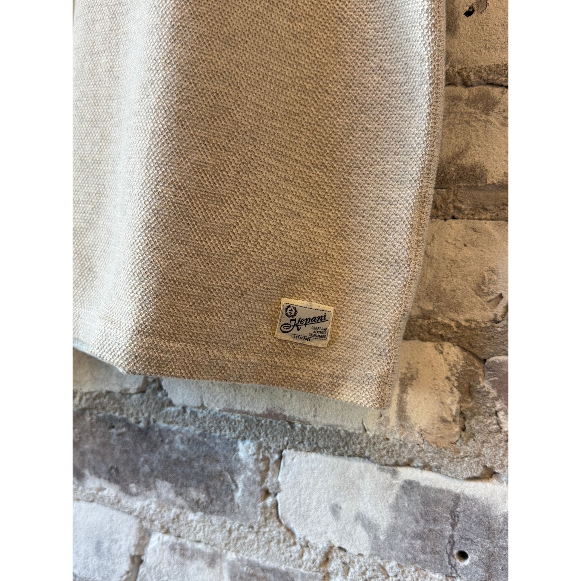 Men's Kepani Raffy Pique Knit Polo Shirt in oatmeal, featuring a classic collar and short sleeves, laid flat on a white background.