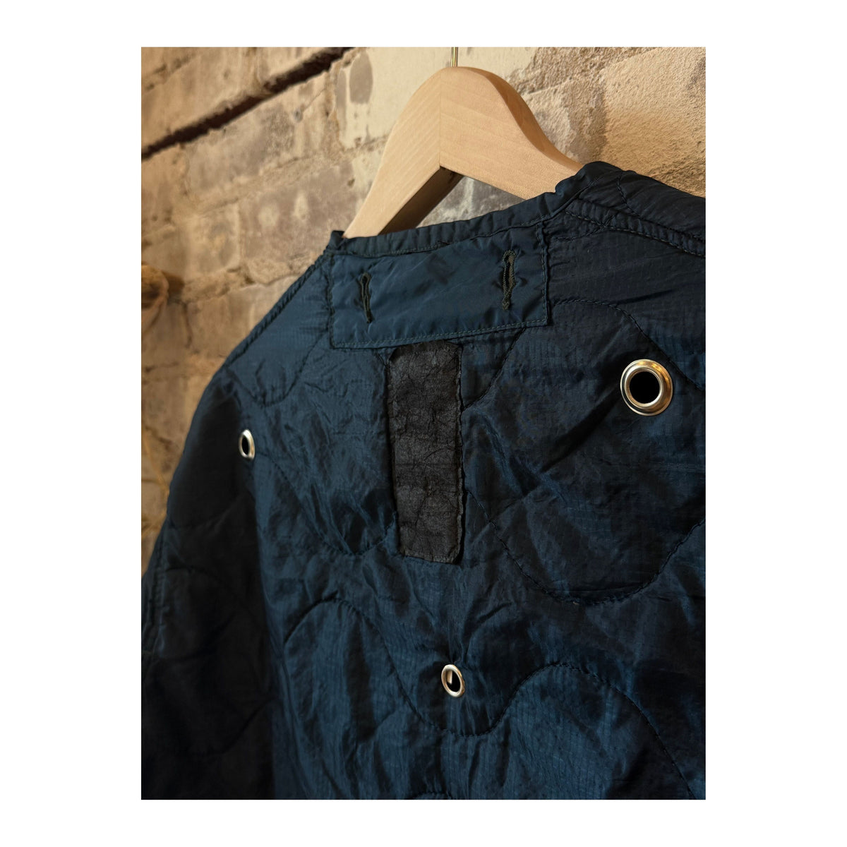 Women's military liner grommets in navy by Sloppy Seconds, close-up of durable metal grommets on navy fabric.