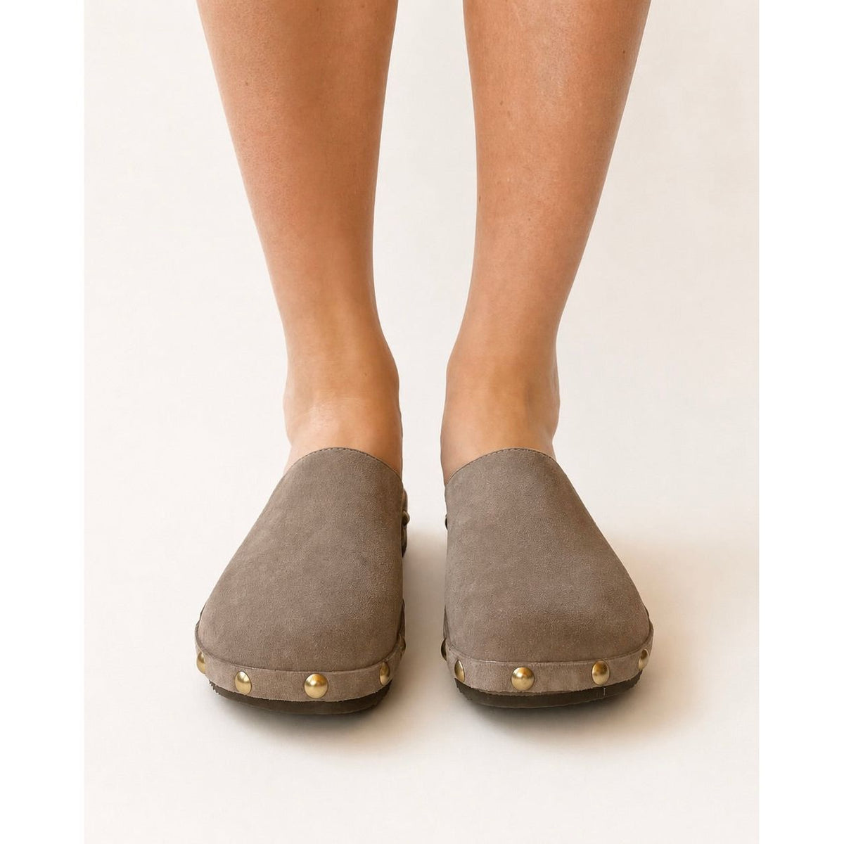 Pair of brown suede clogs with gold studs on a white background