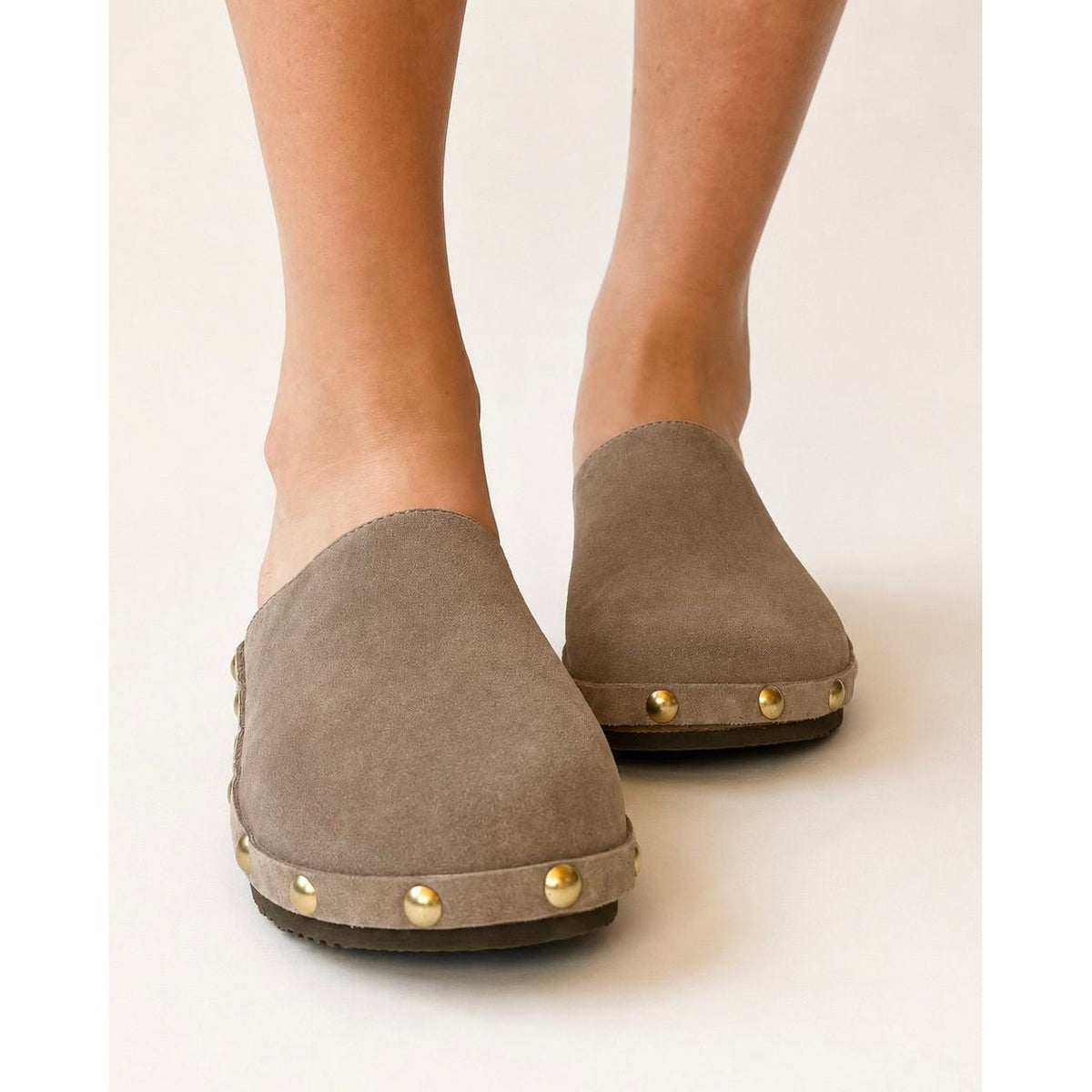 Pair of brown suede clogs with gold studs on a white background