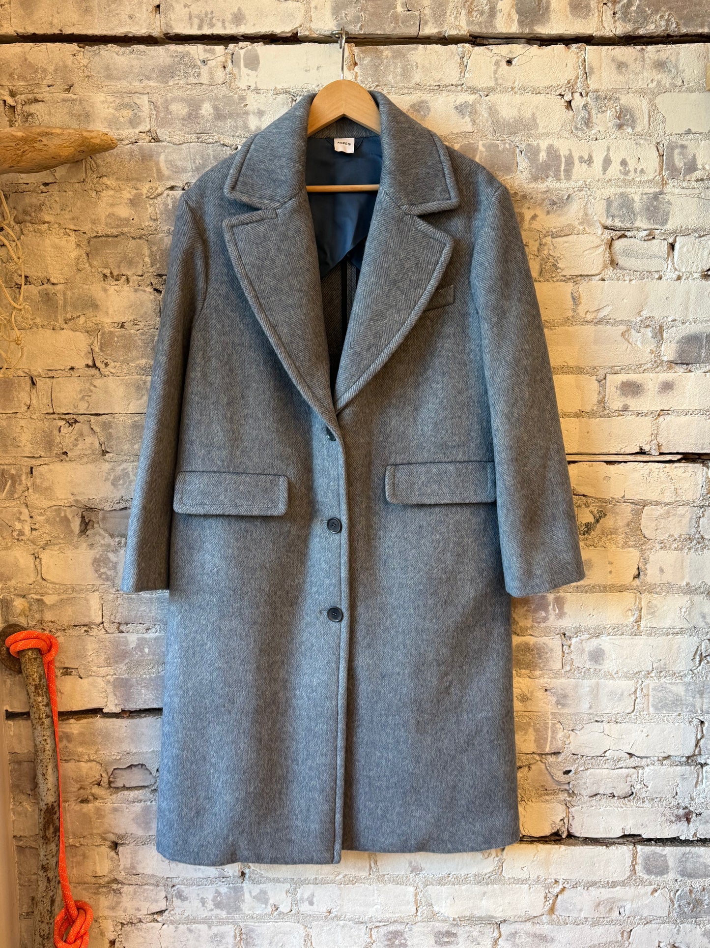 Women's sky blue wool coat by Aspesi, featuring a classic tailored fit and button closure, displayed on a hanger.