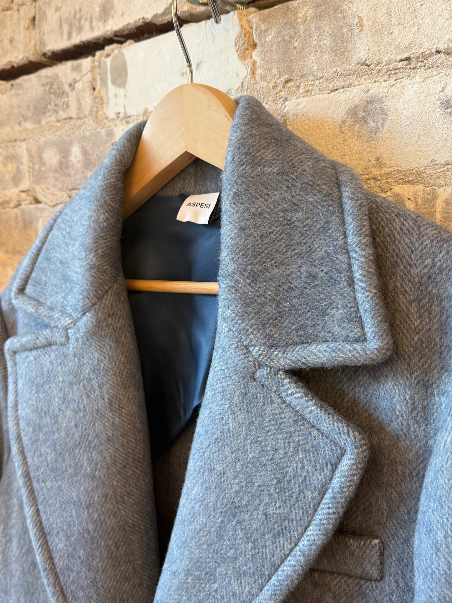 Women's sky blue wool coat by Aspesi, featuring a tailored fit and classic design, displayed hanging on a wooden hanger.
