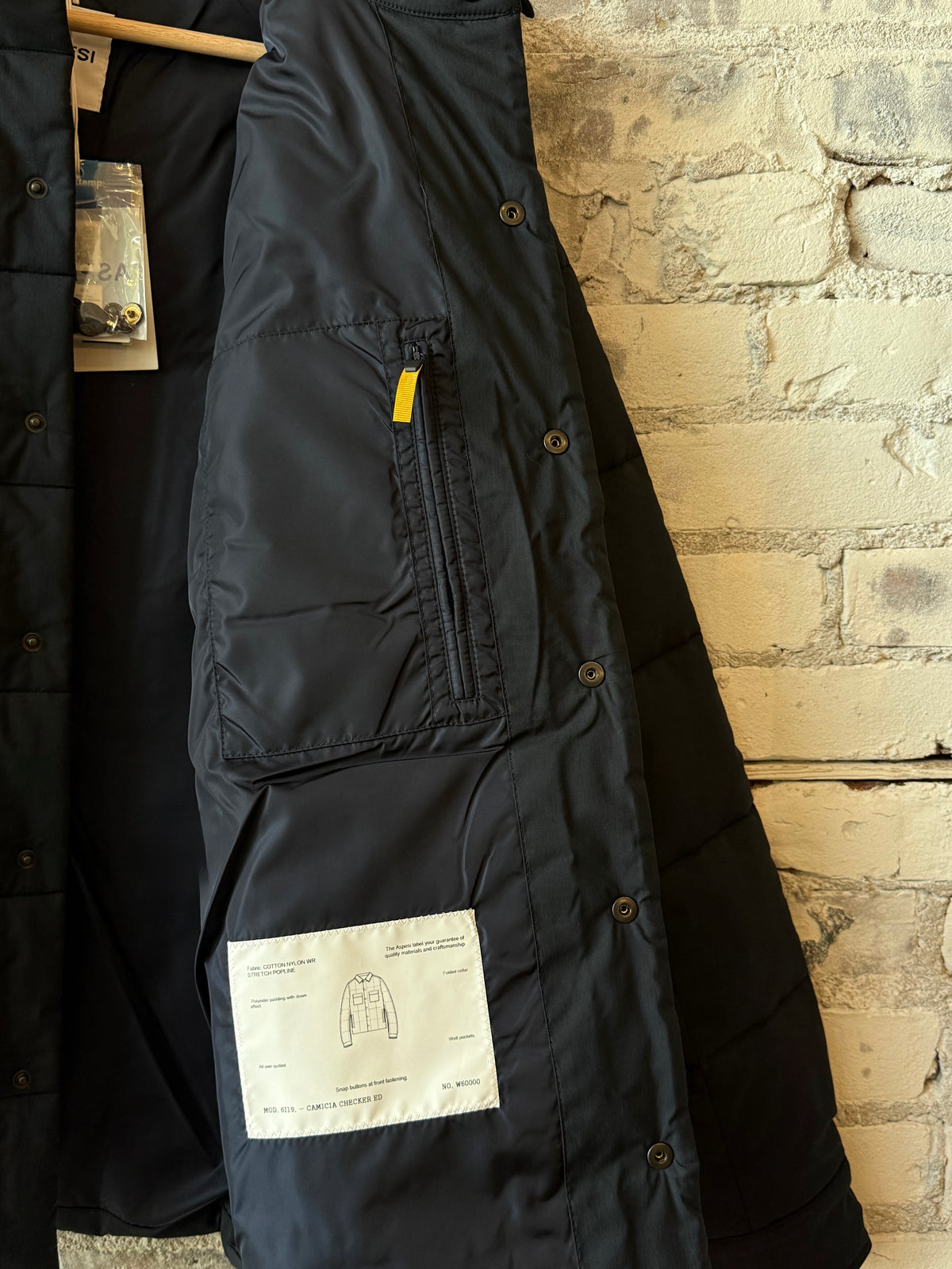 Men's navy padded quilted overshirt by Aspesi, showing a close-up of the insulated, padded fabric and button details.