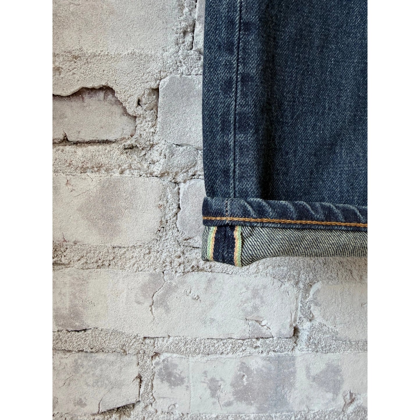 Men's Edwin Akita Regular Tapered 13.5oz selvedge denim jeans in Sagano wash, displayed folded with visible stitching and texture.