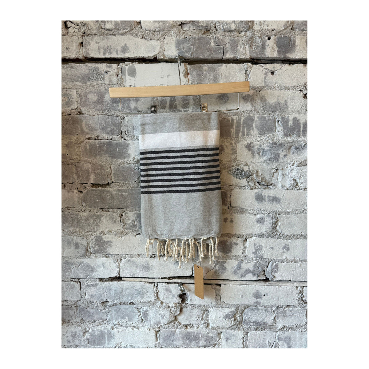Gray and black Wonderfouta beach towel sarong draped on a chair, showcasing lightweight, versatile home accessory for beach and pool.