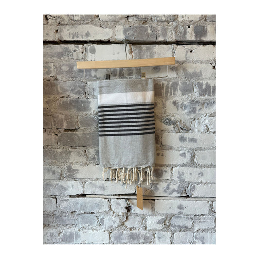 Gray and black Wonderfouta beach towel sarong spread out on a sandy beach, showcasing lightweight, versatile home accessory.