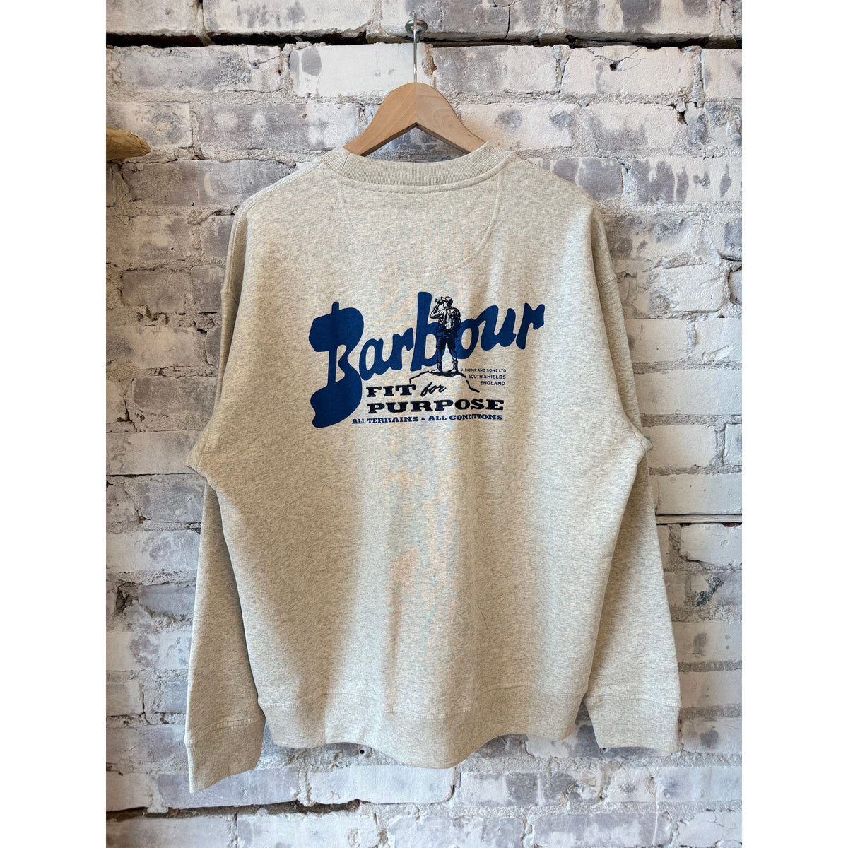 Barbour men's Blythe crew neck jumper in neutral marl, showing the soft knit fabric and classic fit on a hanger.