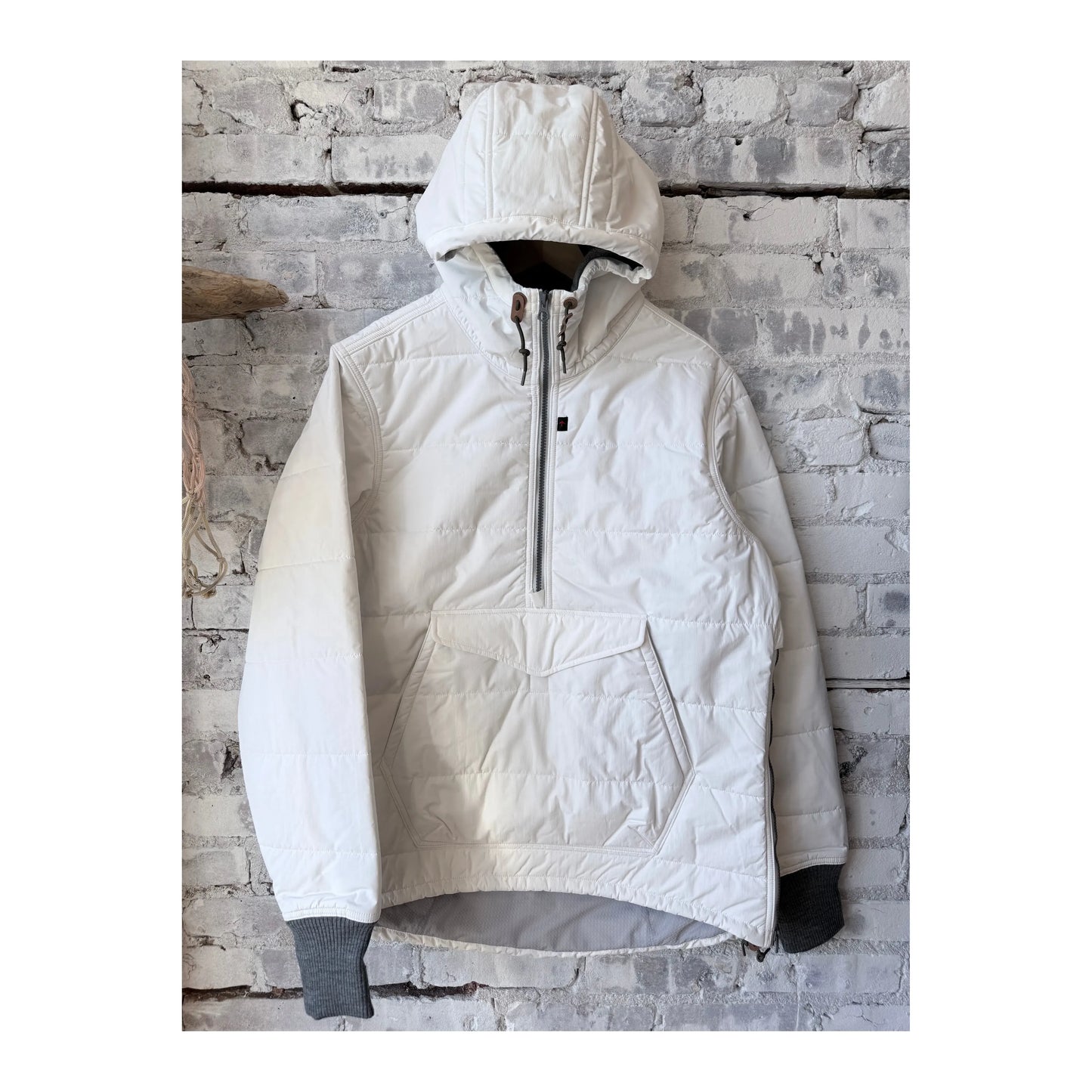 Men's white Boarder Anorak jacket by Relwen, featuring a lightweight design and adjustable hood, displayed on a hanger.