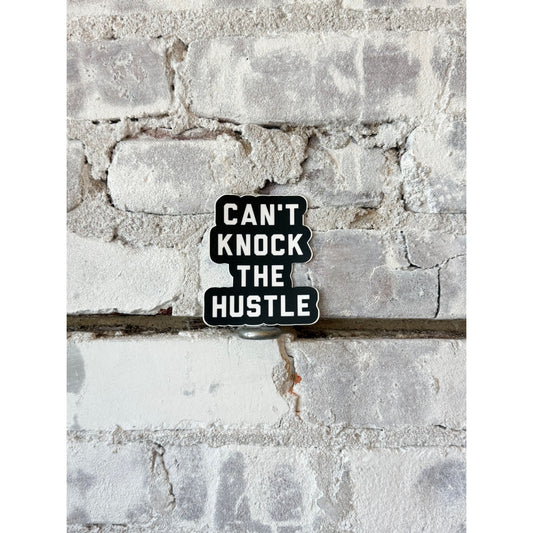 Black and white "Can't Knock the Hustle" sticker by N.B. GOODS, featuring bold text on a durable adhesive accessory.