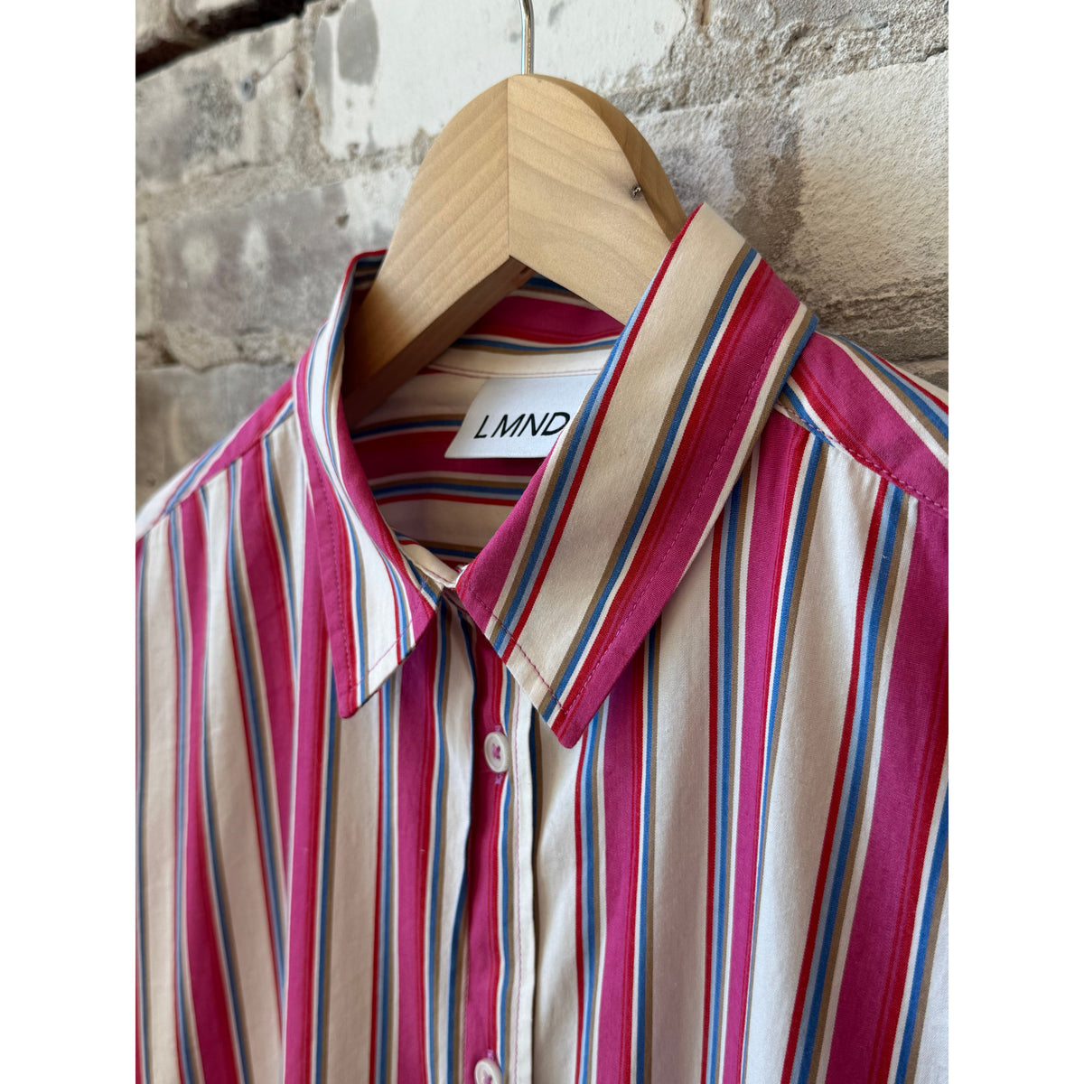 Women's Chiara Midi Dress by LMND in vibrant fuchsia with multicolor stripes, displayed on a hanger against a neutral background.