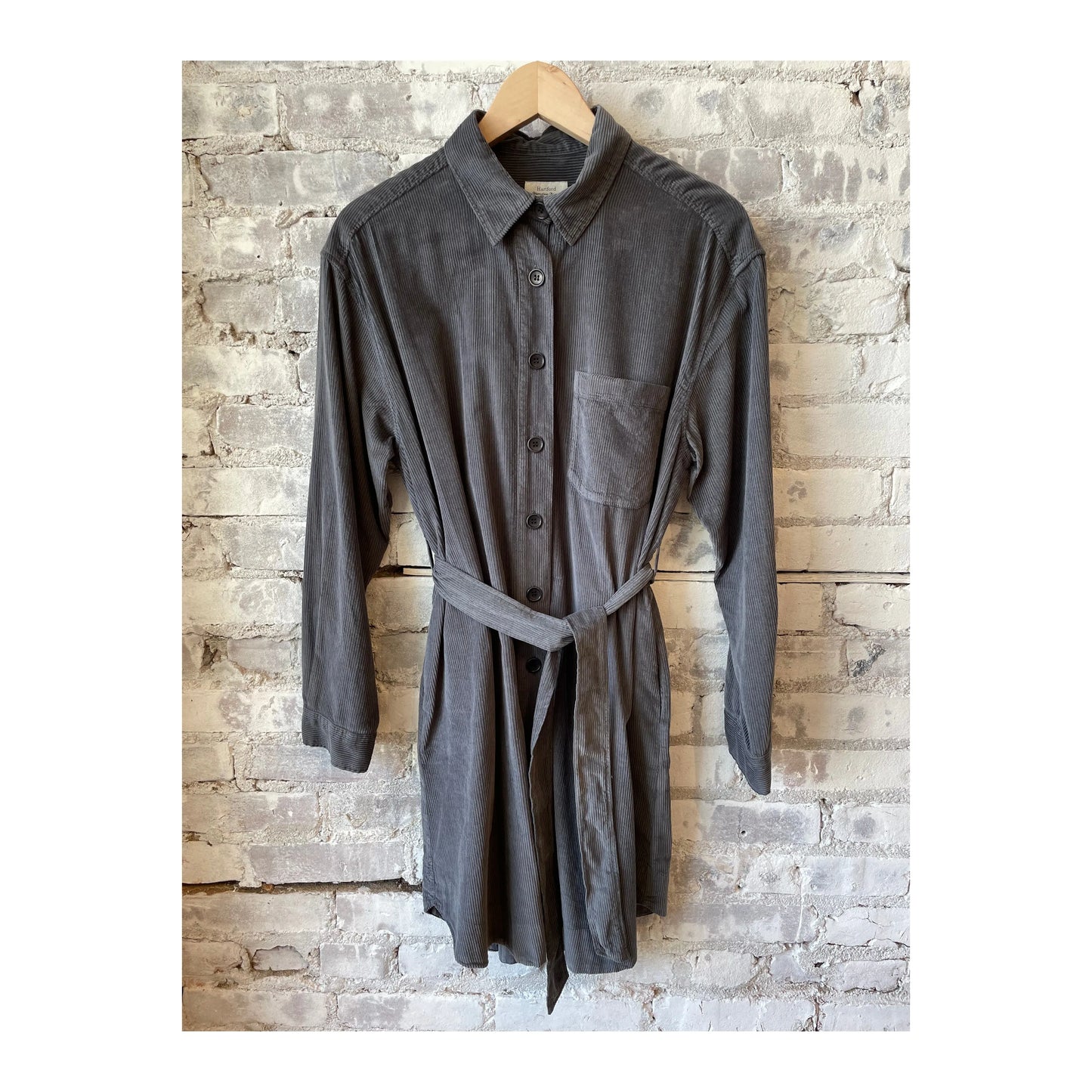 Charcoal Hartford Women's Corduroy Revol Dress hanging on a wooden hanger, showcasing its textured fabric and classic design.