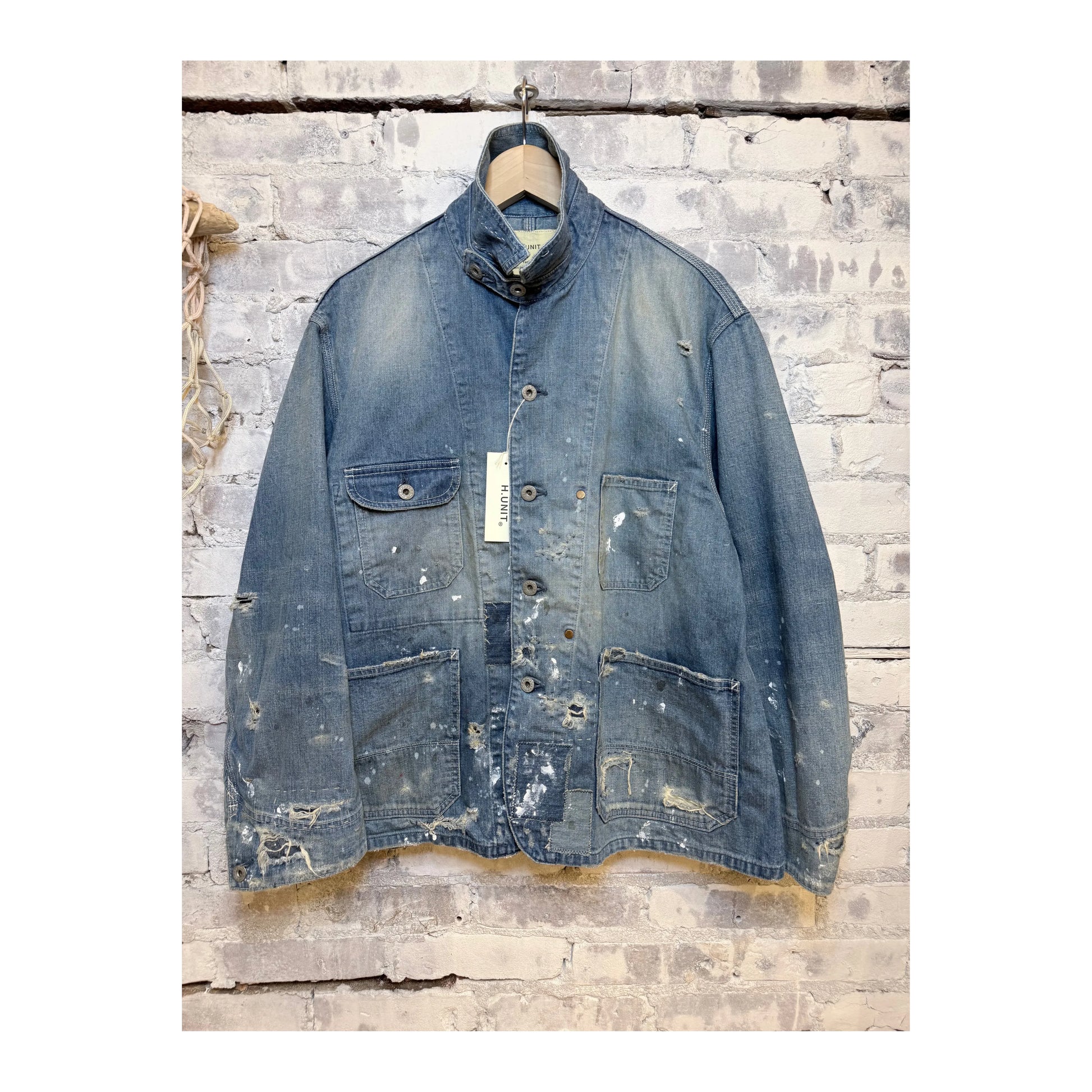 Men's customized indigo denim coverall jacket by H-Unit, featuring fitted design and detailed stitching on a hanger.