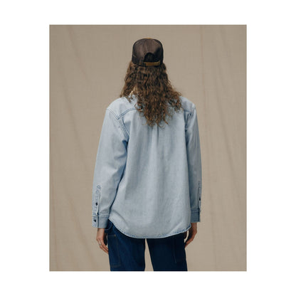 Women's light indigo denim work shirt by FILSON, showing the classic button-up design with chest pockets and long sleeves.