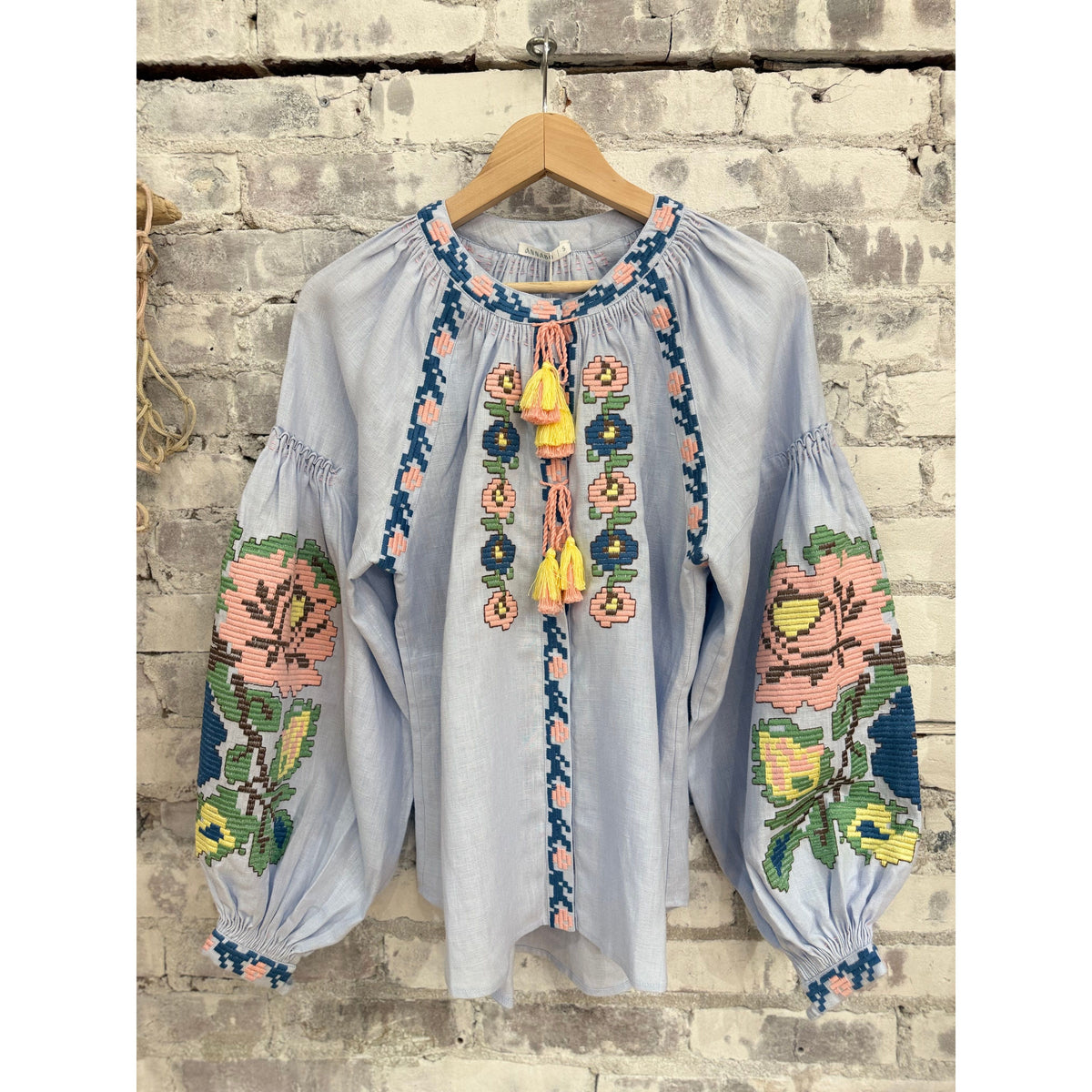 Light blue Annabo women's Elysian Whisper blouse, soft fabric with a relaxed fit and subtle detailing, displayed on a hanger.