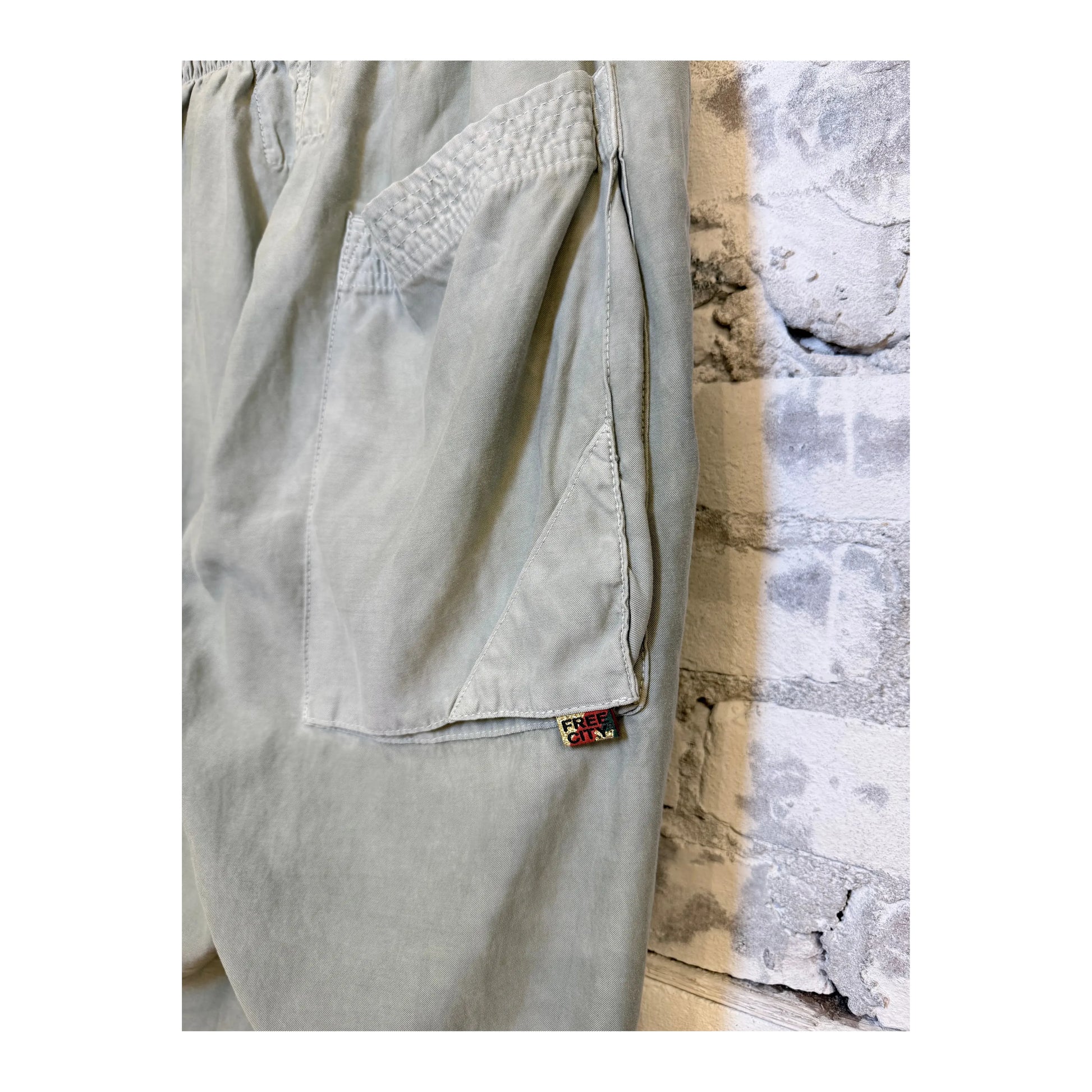 Women's Freecity AirJump pants in silver rock with flap and snap-free matte satin fabric, shown in a stylish side view.