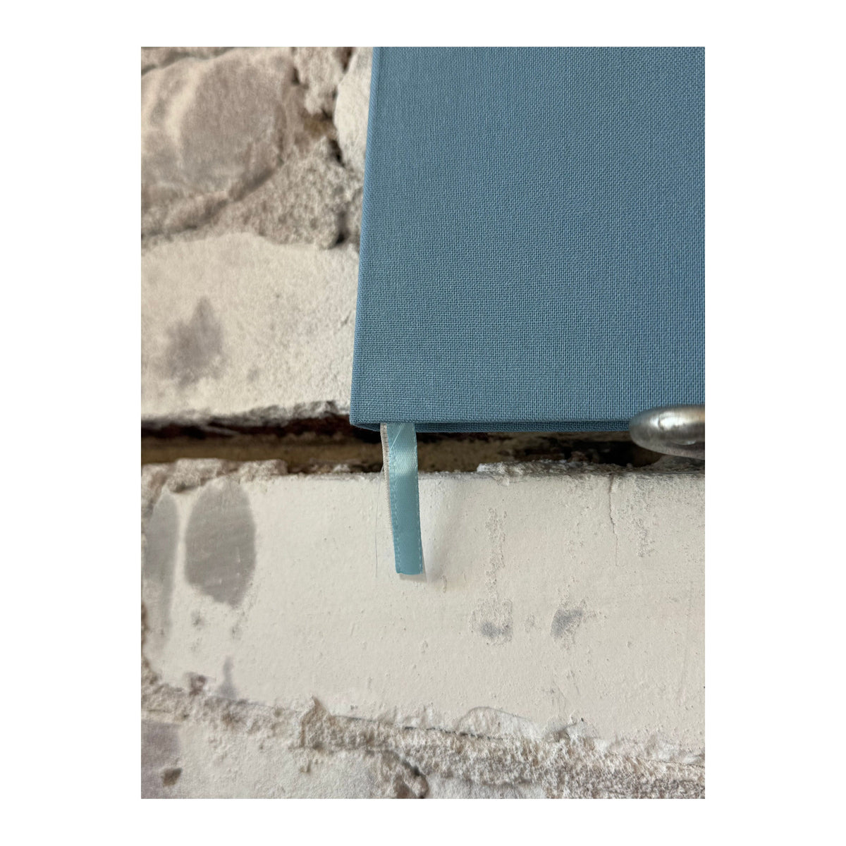 Foil embossed linen notebook in dusty blue with gold accents, styled as a home accessory from Studio Portmanteau.