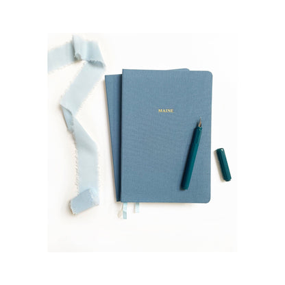 Foil embossed linen notebook in dusty blue with gold accents, designed by Studio Portmanteau, for home accessories and stationery.