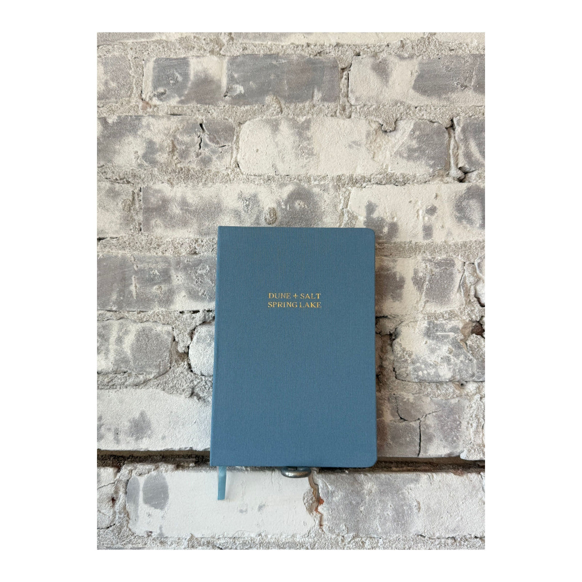 Foil embossed linen notebook in dusty blue with gold accents, designed by Studio Portmanteau for stylish home accessories.