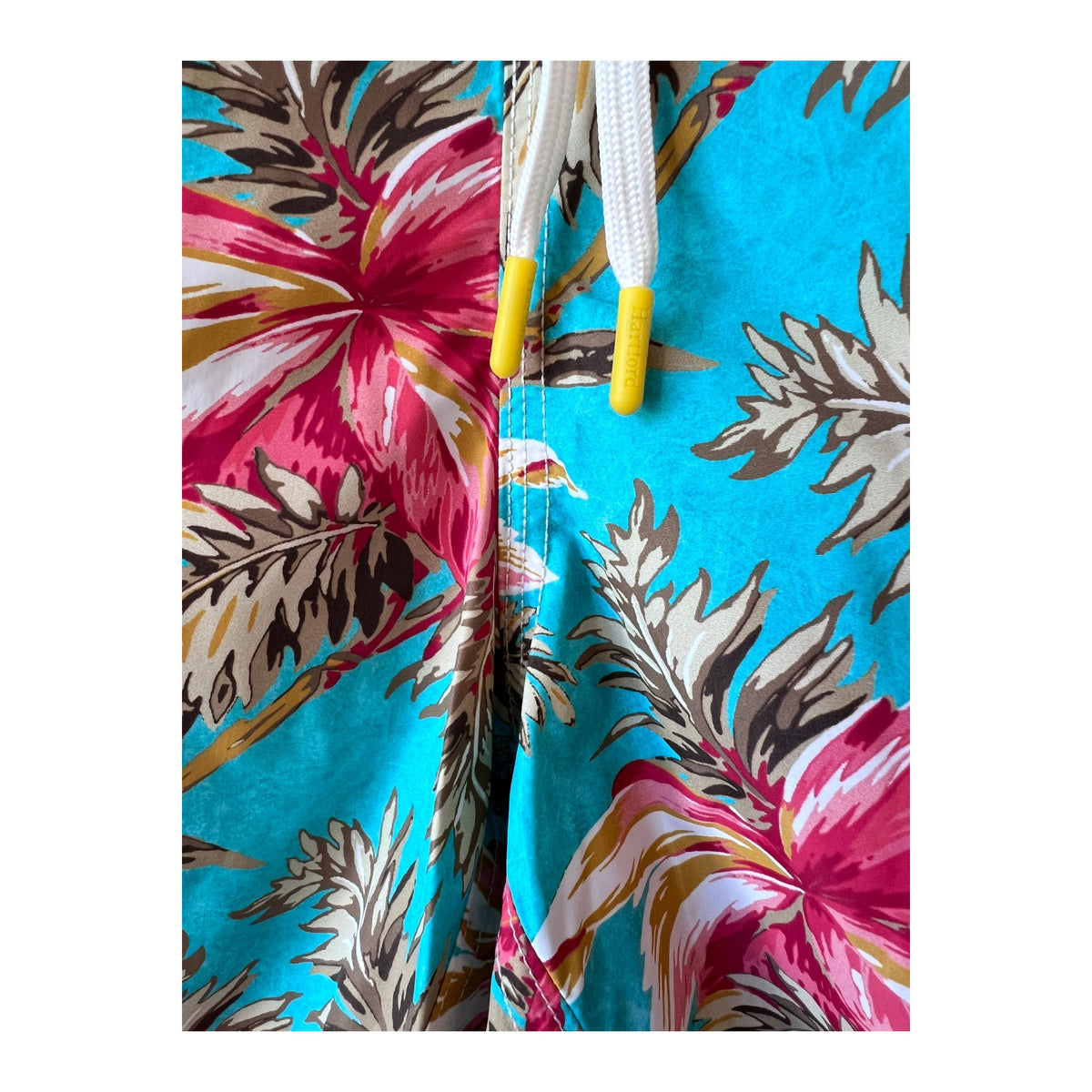 Men's printed turquoise swim trunks by Hartford Men's, featuring a vibrant tropical pattern and comfortable fit.