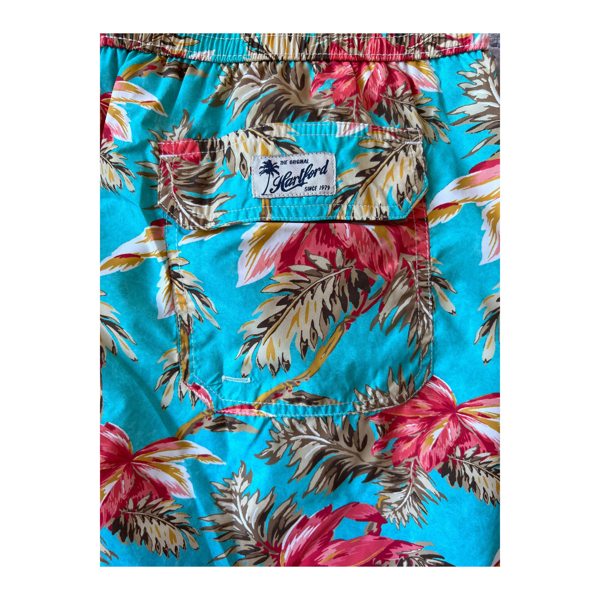 Men's printed turquoise swim trunks by Hartford Men's with vibrant tropical pattern and comfortable fit.