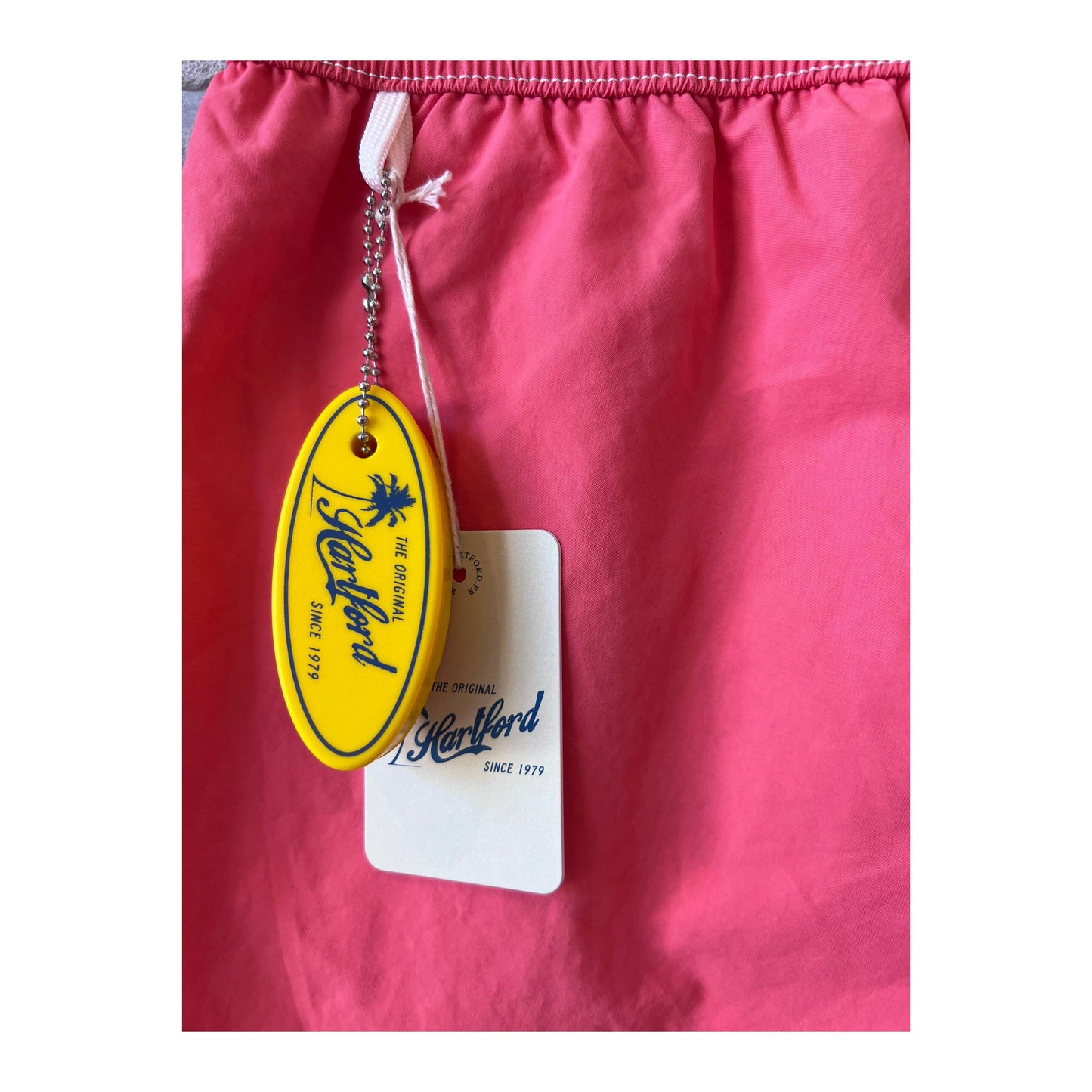 Men's Hartford Classic Swim Trunks in faded coral with matching pochette, featuring a relaxed summer style.
