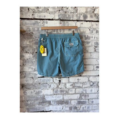 Men's classic swim trunks and sage pochette from Hartford Men's, displayed on a neutral background.