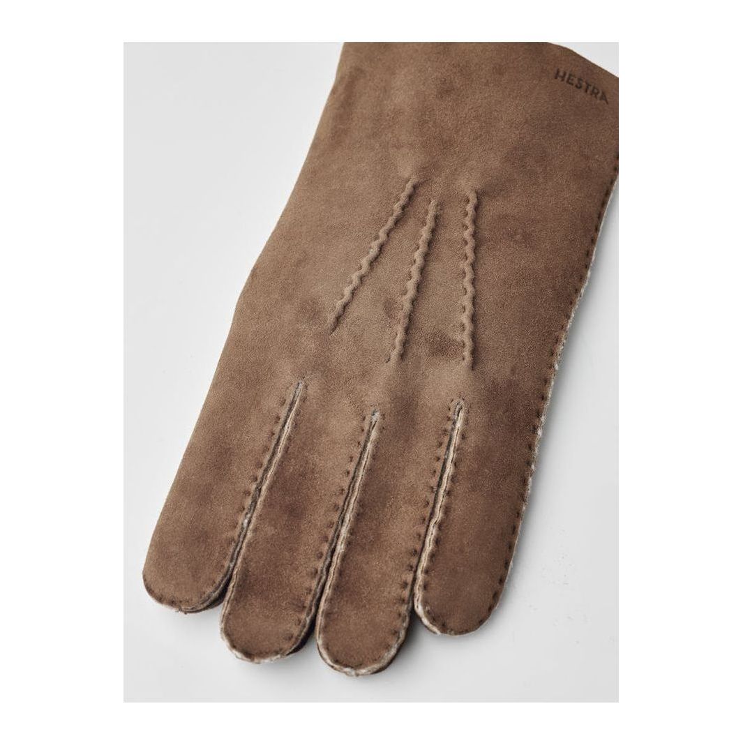 Men's Hestra Bernard glove in brown leather, showing the textured exterior and detailed stitching for a stylish winter accessory.
