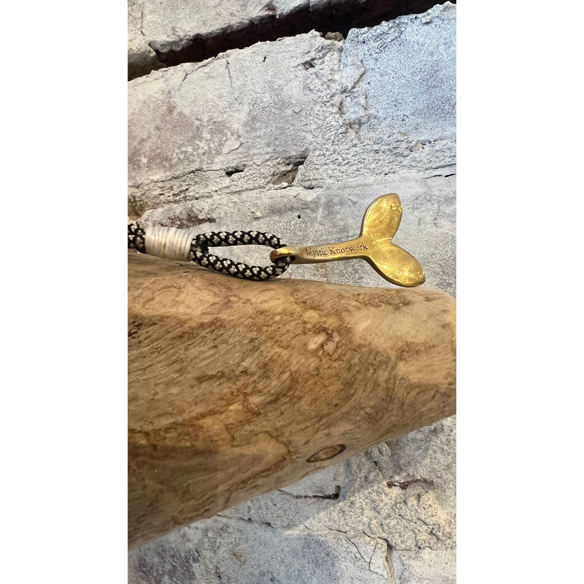 Men's brass whale tail pendant featuring black diamond accents, crafted by Mystic Knotworks, with nautical design details