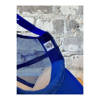 Royal blue trucker hat by N.B. GOODS featuring United States vs. Bruce Springsteen graphic and adjustable mesh back.