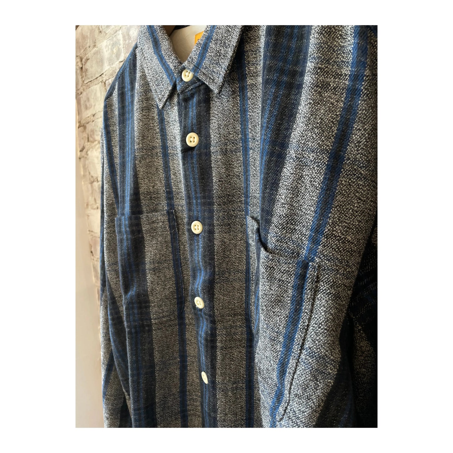 Men's N°111 round tail over shirt in gray, blue, and black from Madras Trading, displayed on a hanger.
