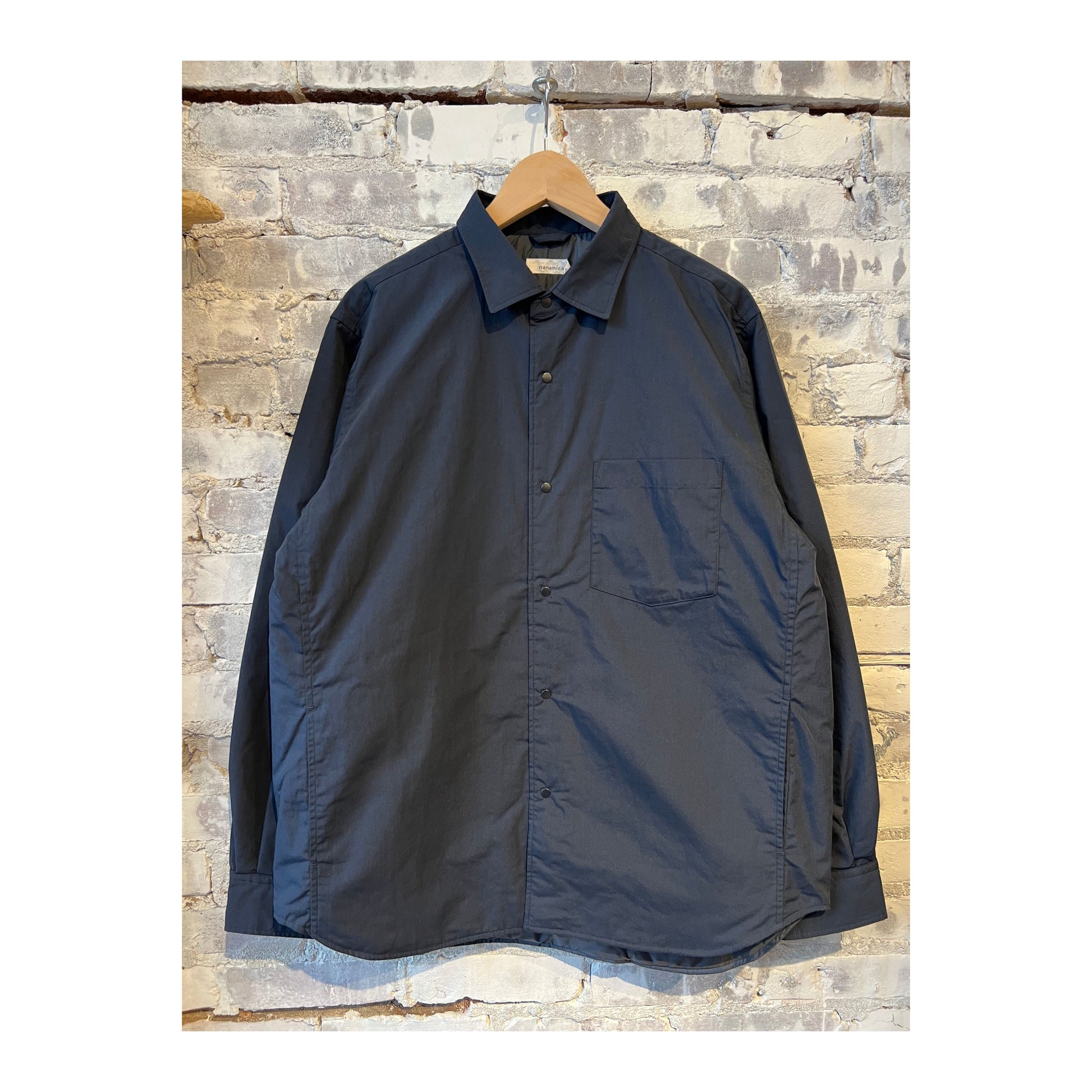 Men's nanamica insulation shirt jacket in dark navy, showing the insulated shirt jacket with front button closure and collar detail.